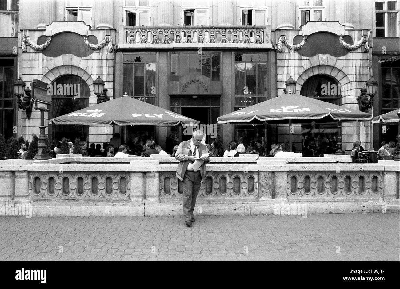 Blick auf Bupapest zum Zeitpunkt der neunziger Jahre. -1990 - Ungarn / Budapest - Blick auf Bupapest zum Zeitpunkt der neunziger Jahre. -Alltägliche Szene. Ein Mann liest ein Buch am Eingang der u-Bahnstation "Foldalatti"; in der Zwischenzeit einige Touristen und Ungarn sitzen Oustide eines großen Restaurants von der quadratischen Hosok Tere (Heldenplatz) - Philippe Gras / Le Pictorium Stockfoto