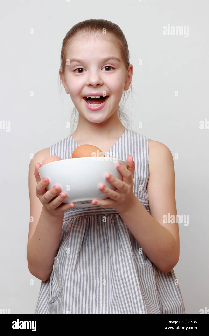 Fröhliches kleines Mädchen hält Keramikschale mit Bio-Eiern Stockfoto