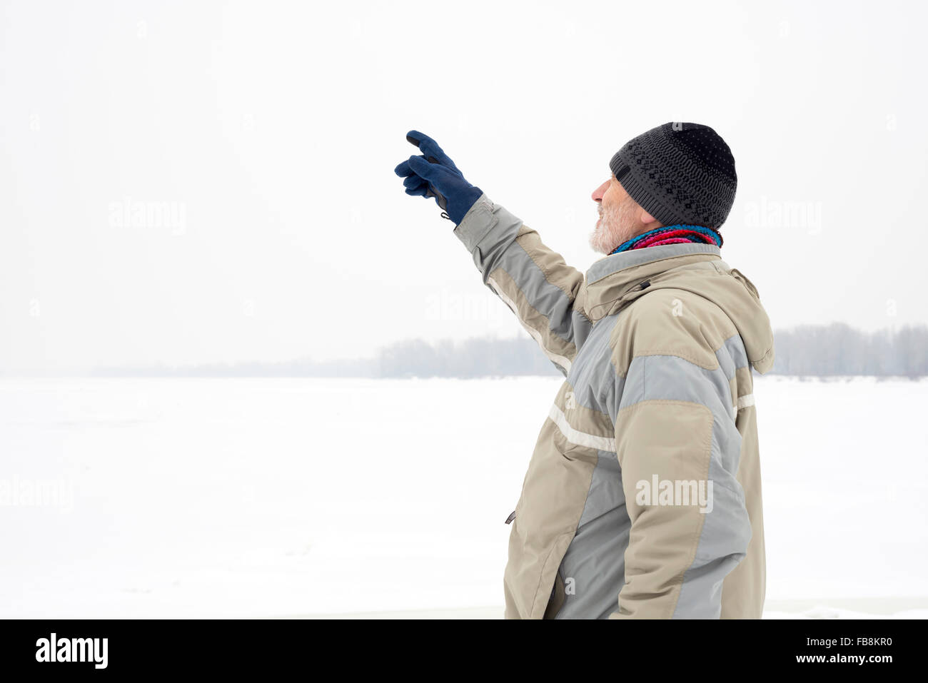 Ein Mann mit einer Mütze, eine Regenjacke und eine Mütze ist etwas mit dem Finger in der Nähe des Dnepr Flusses Dur angibt. Stockfoto