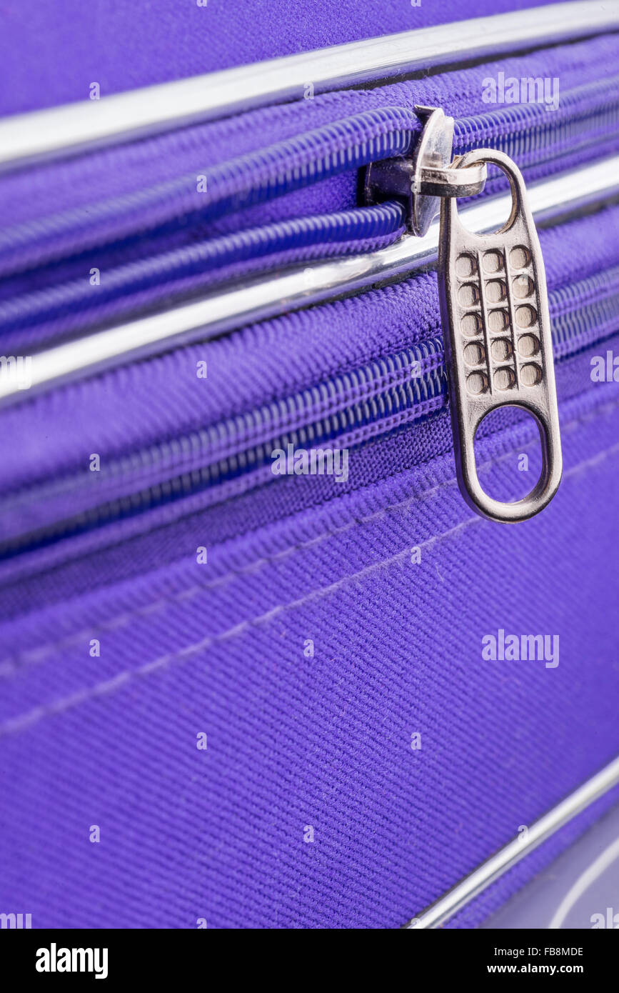 Makro eines Reißverschlusses zeigt die Grifflasche und die Kette auf einem violetten Koffer bereit für einen sicheren Urlaubsreisen Stockfoto