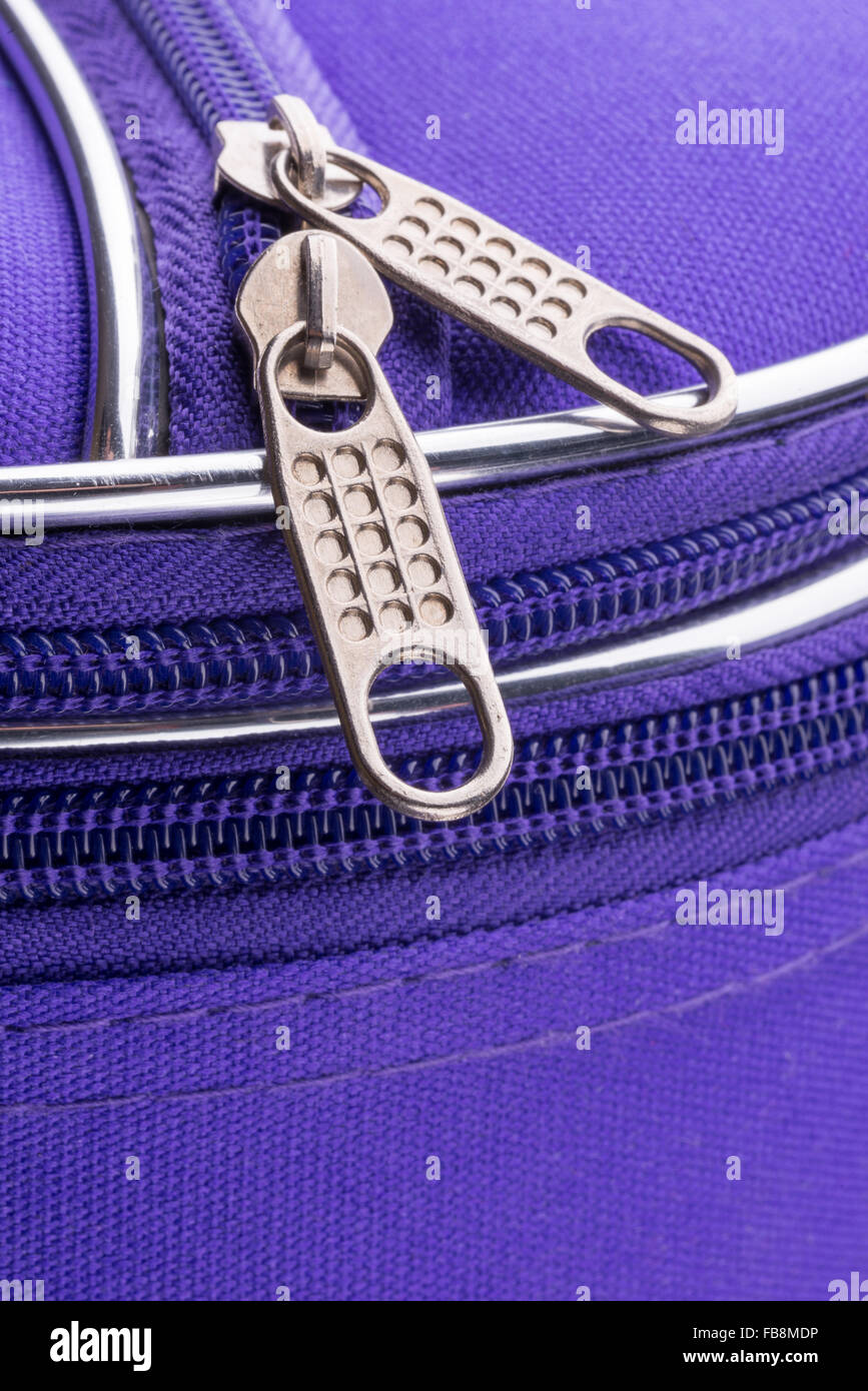 Makro eines Reißverschlusses zeigt die Grifflasche und die Kette auf einem violetten Koffer bereit für einen sicheren Urlaubsreisen Stockfoto