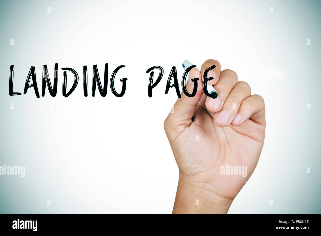 Nahaufnahme der Hand von einem kaukasischen Jüngling schreiben die Text-Landing-Page im Vordergrund Stockfoto