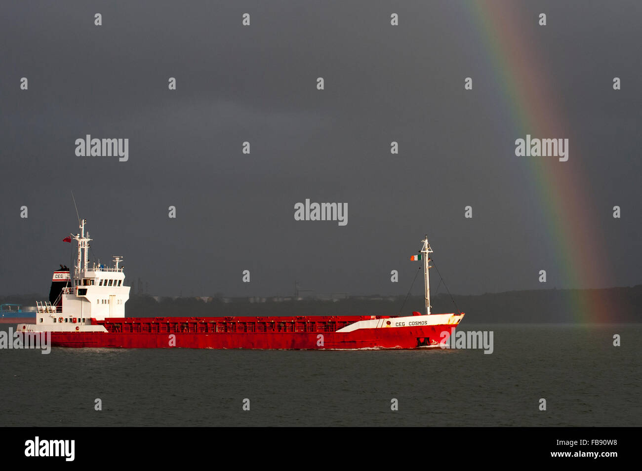 MV CEG Kosmos segelt in den Hafen von Cork, Irland, durch einen Regenbogen unter Gewitterhimmel. Stockfoto