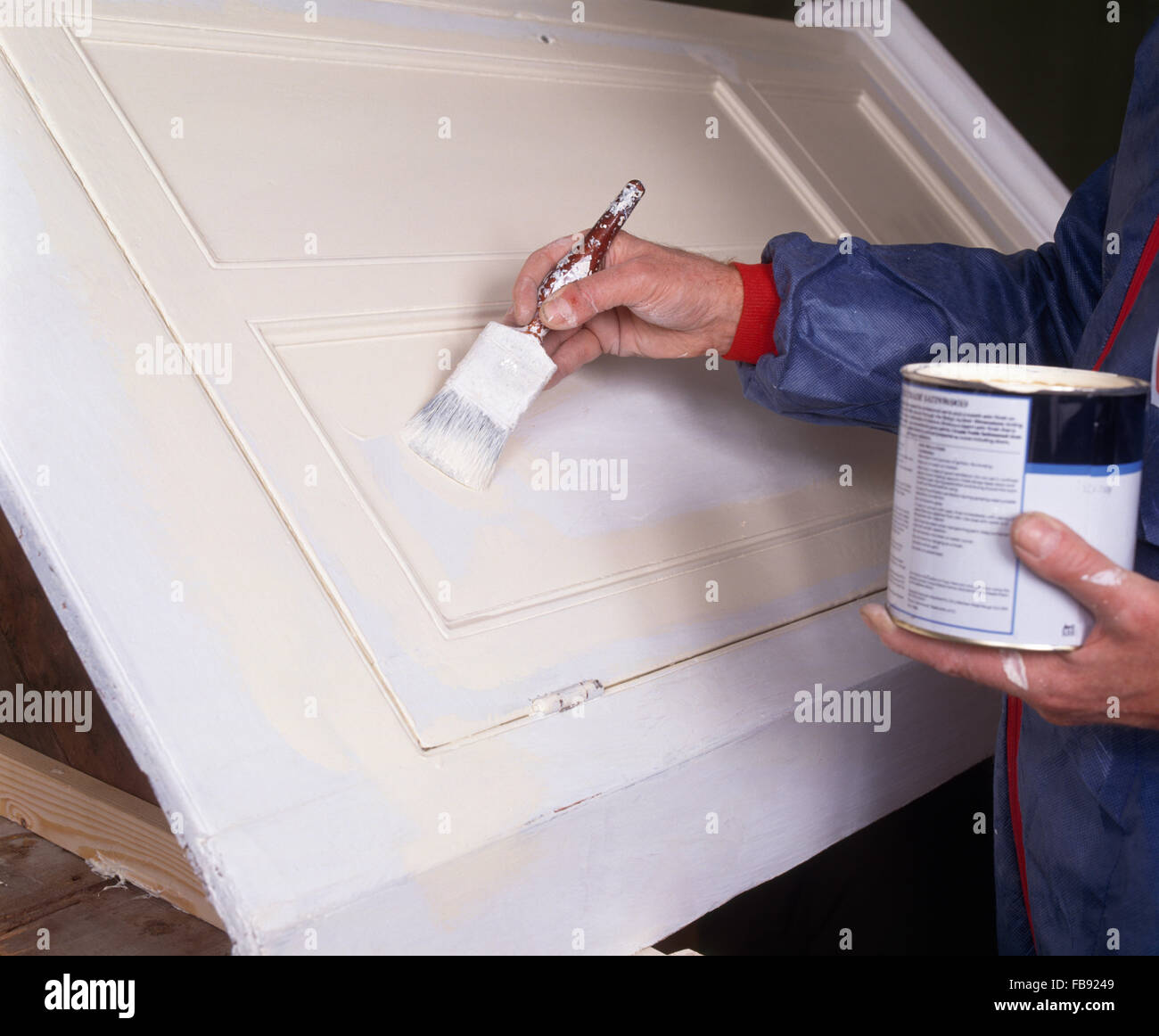 Nahaufnahme der Dekorateur hält eine Dose mit weißer Farbe und malen eine Holztür Stockfoto