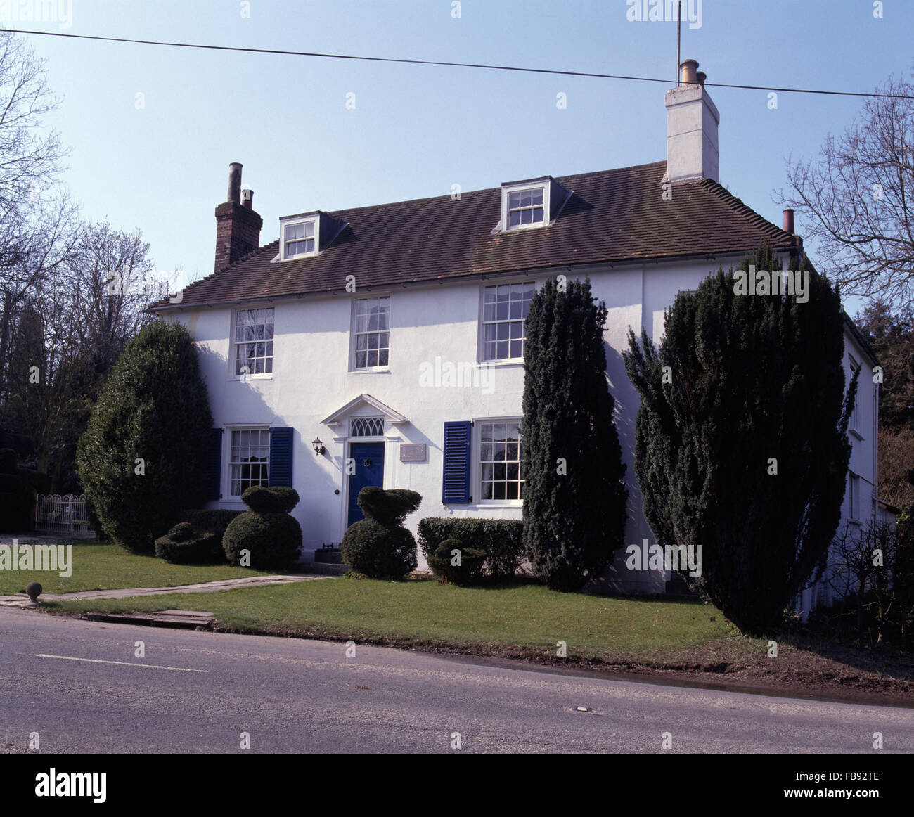 Außen von einem weißen viktorianischen Landhaus mit hohen Eiben auf dem Rasen Stockfoto