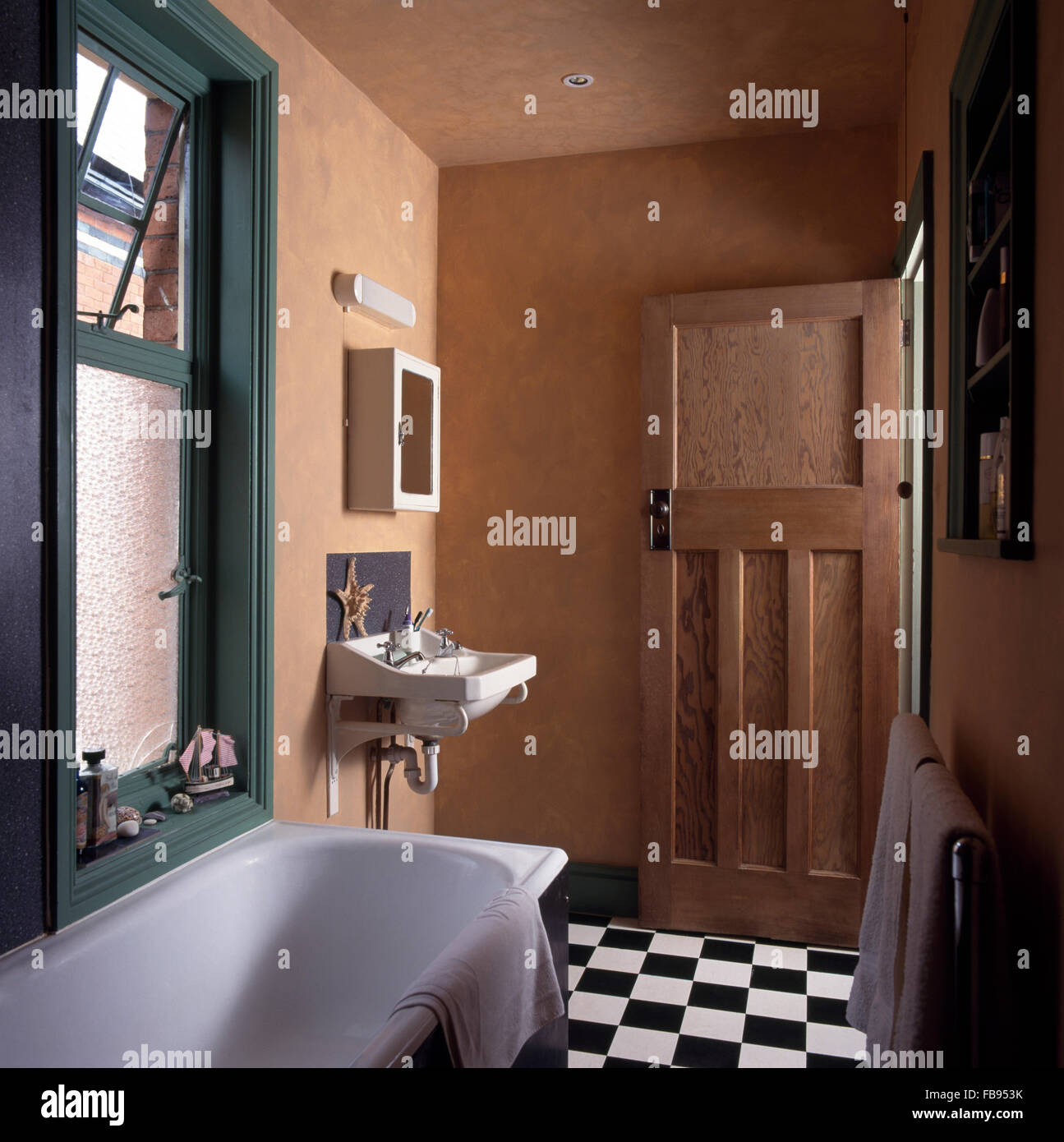 Schwarz + weiß Checker-Bord Boden in einem 30er Jahre Stil Badezimmer mit  einem dunklen grünen Fenster über der Badewanne Stockfotografie - Alamy