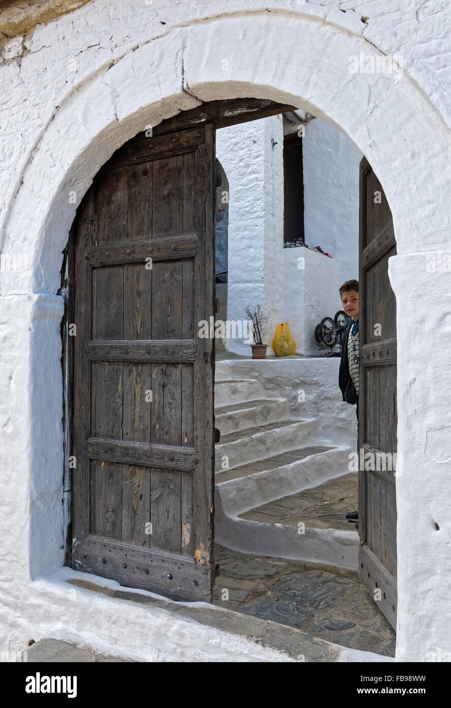 Ein Junge sieht durch die halb offene traditionelle Holztür seines Hauses am 12. April 2015 in Berat, Albanien. Stockfoto