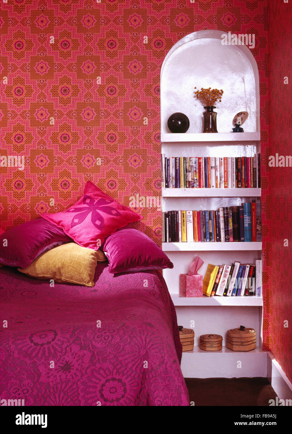 Fuchsie pinke Kissen auf dem Bett mit rosa Spanisch Bett Abdeckung der sechziger Jahre mit rosa Hintergrund und weißen Alkoven Regale Schlafzimmer Stockfoto