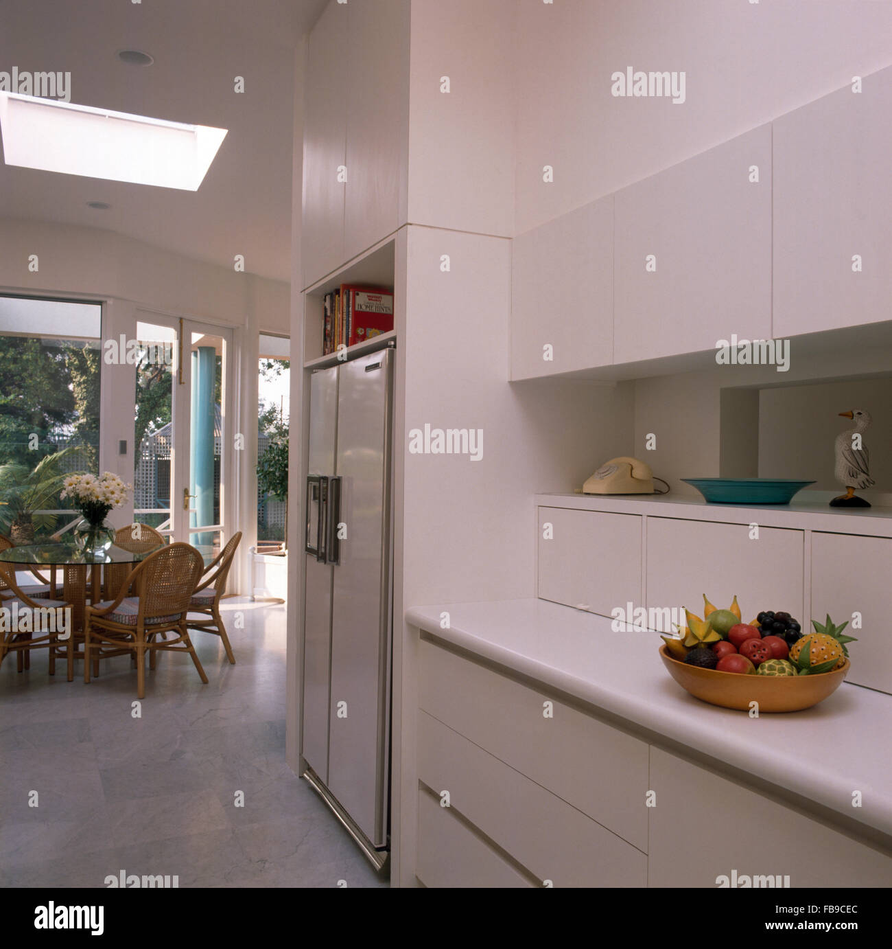 Großer Kühlschrank mit Gefrierfach in weißen Architektur Küche mit Rohrstock zurück Stühle an einem Tisch aus Glas Stockfoto
