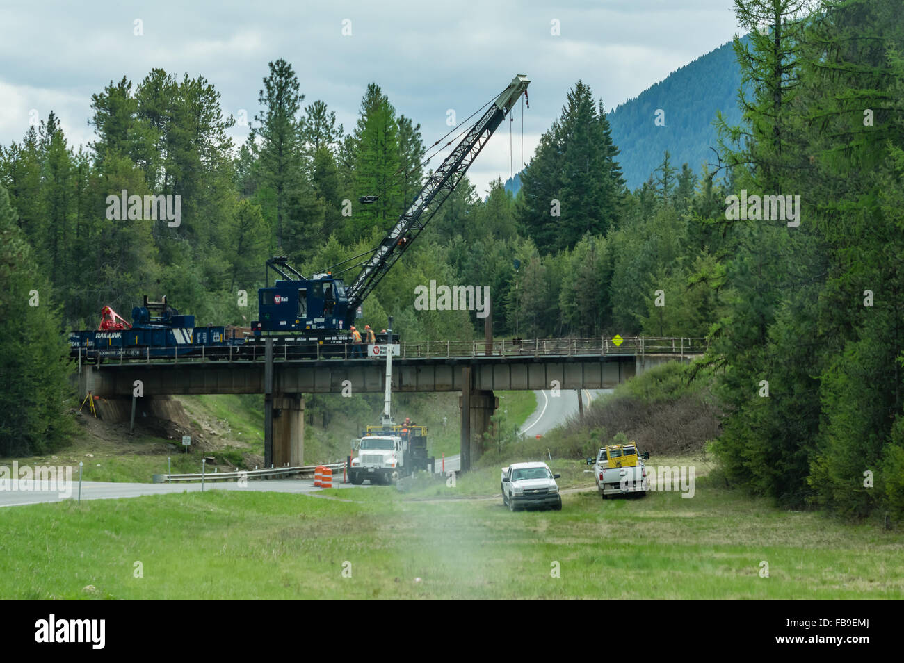 Arbeitnehmer mit einem mobilen Kran, um einen Teil des Titels einer Eisenbahnbrücke zu reparieren.  Forelle-Nebenfluß, Montana, USA Stockfoto