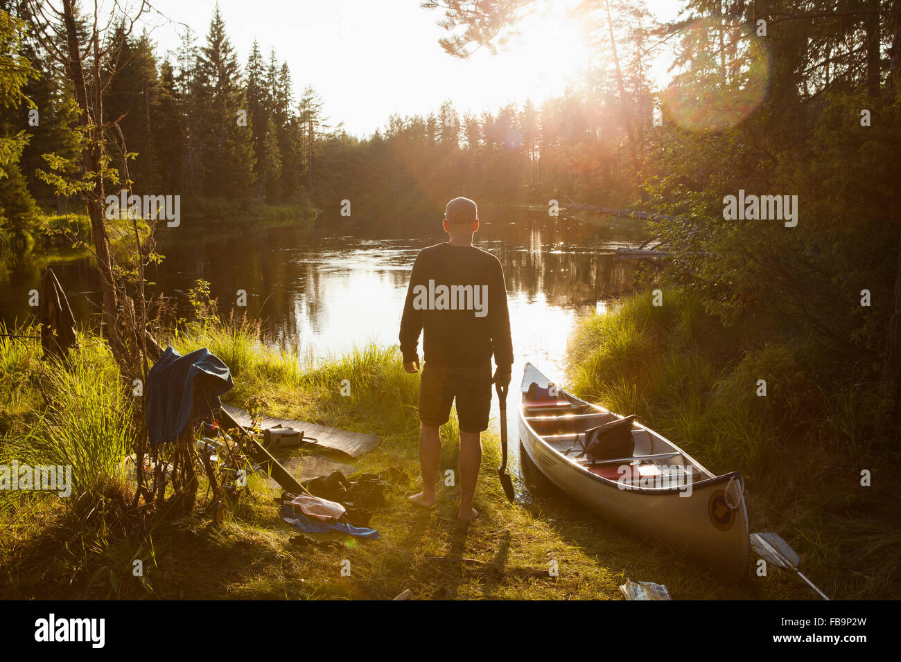 Schweden, Vastmanland, Svartalven, Mann mit dem Kanu am Ufer Stockfoto