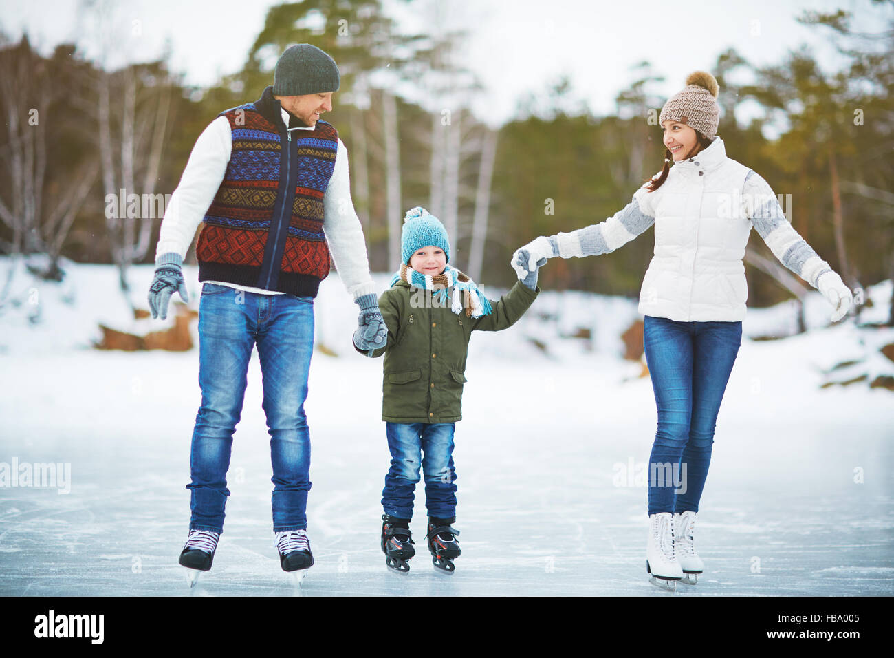 Junge Familie halten Hände und Eislaufen am Eislaufplatz Stockfoto