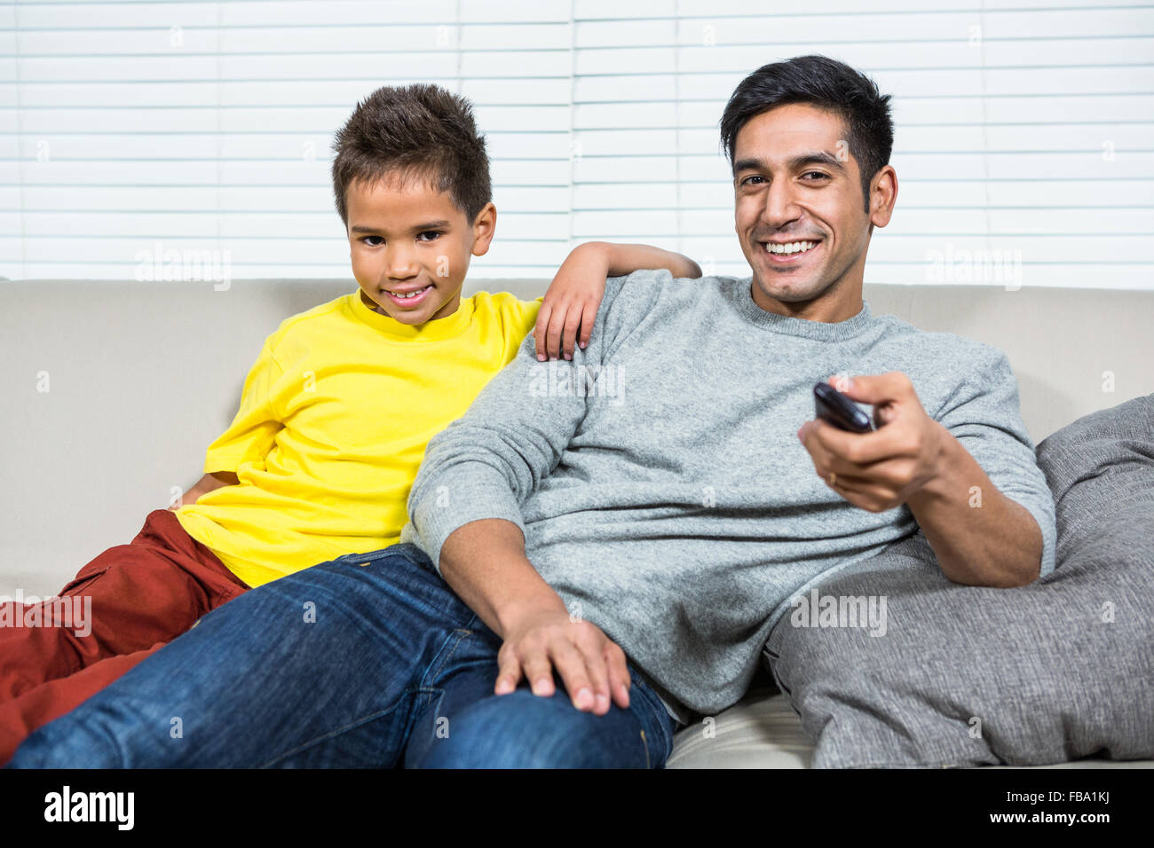 Lächelnd, Vater und Sohn auf dem Sofa vor dem Fernseher Stockfoto