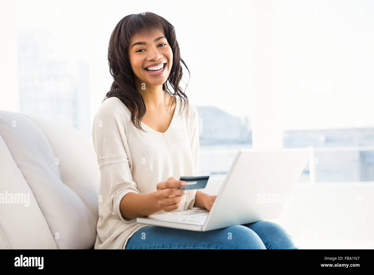 Lächelnde lässige Frau Dinge mit ihrem Laptop kaufen Stockfoto