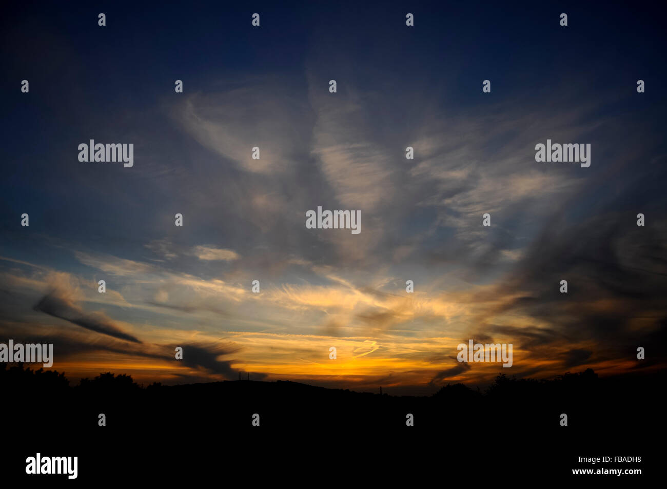 Licht nach Sonnenuntergang mit hohen Wolkenfetzen am Himmel zu verblassen. Stockfoto