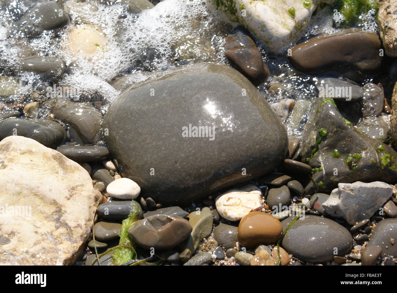 Stein Texturen Hintergrund. Meer-Steinen bei Sonnenschein mit Meereswellen und Schäume. Stockfoto
