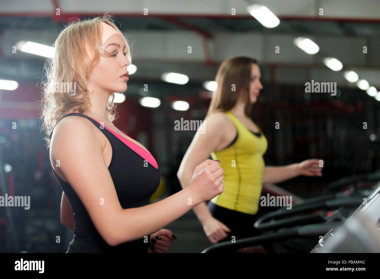Zwei sportliche Mädchen laufen auf Rennstrecke im Fitness-Studio Stockfoto