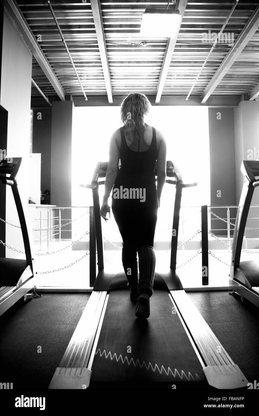 Sportliche Mädchen in Sportbekleidung geht auf Cardio-Trainer, Laufband im Fitnessstudio (Ansicht von hinten) Stockfoto