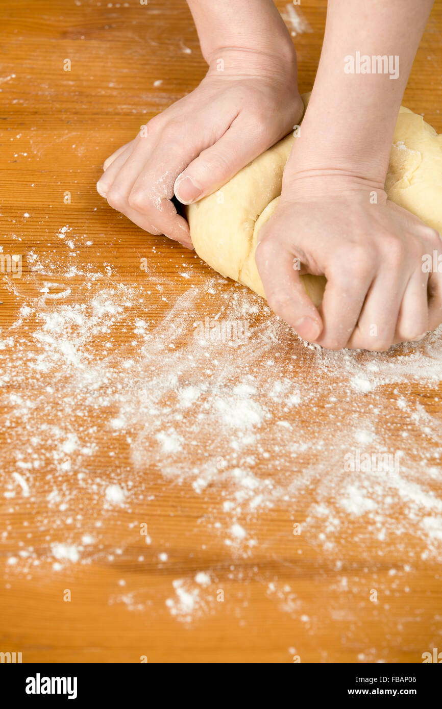 Schließen Sie Hausmannskost, weibliche Hände kneten Paste auf Holztisch mit Mehl bedeckt Stockfoto