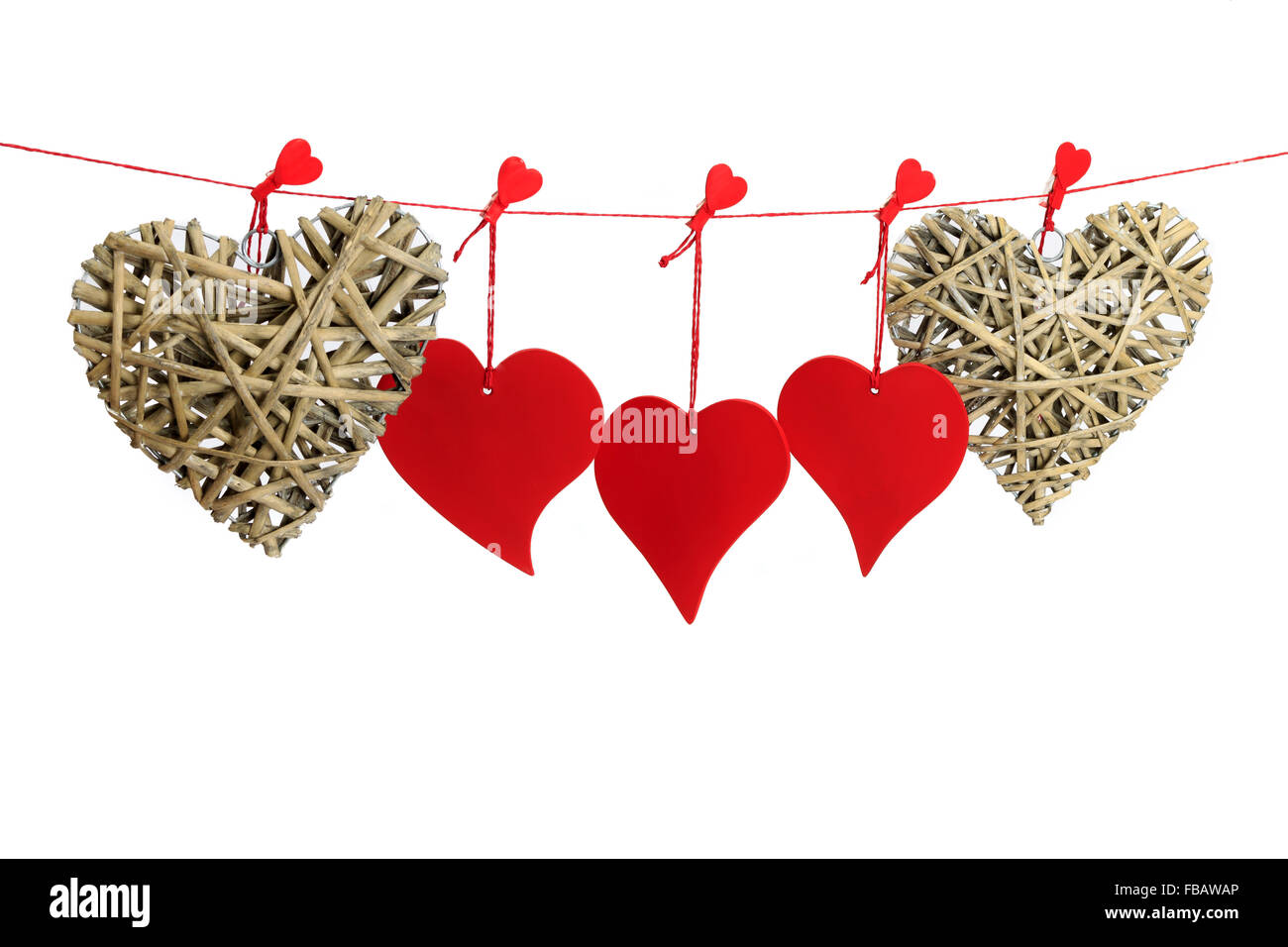 Drei rote und zwei Wicker Valentine Herzen hängen von einer roten Schnur isoliert auf weißem Hintergrund Stockfoto