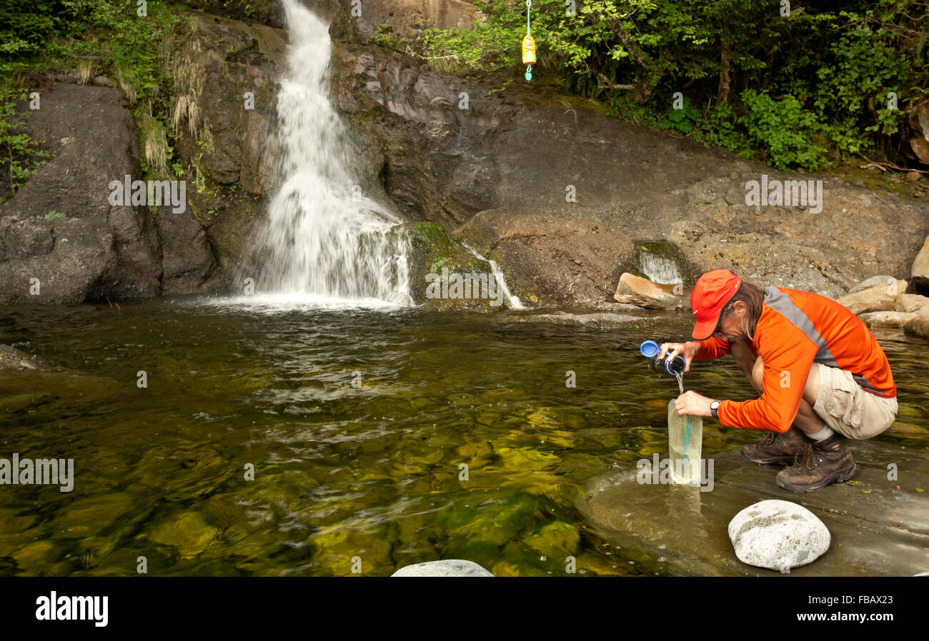 BRITISH COLUMBIA - Wanderer Füllung Wasserflaschen an der Basis des Tsocowis Creek Falls entlang der West Coast Trail am Tsocowis Creek. Stockfoto