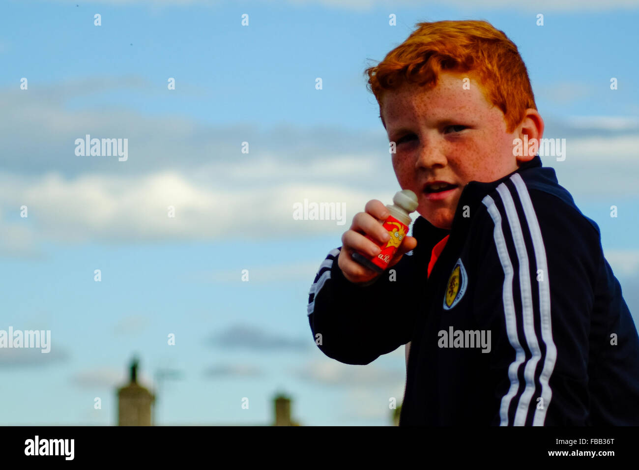 Ein schottische junge mit roten Haaren genießt ein Bonbon am Strand in Lossiemouth, Schottland. Stockfoto