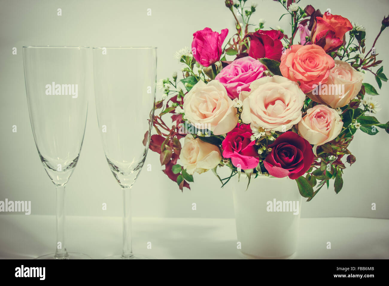 Vase mit Rosen und Champagner Glas auf weißem Hintergrund setzen schöne Blume Stockfoto