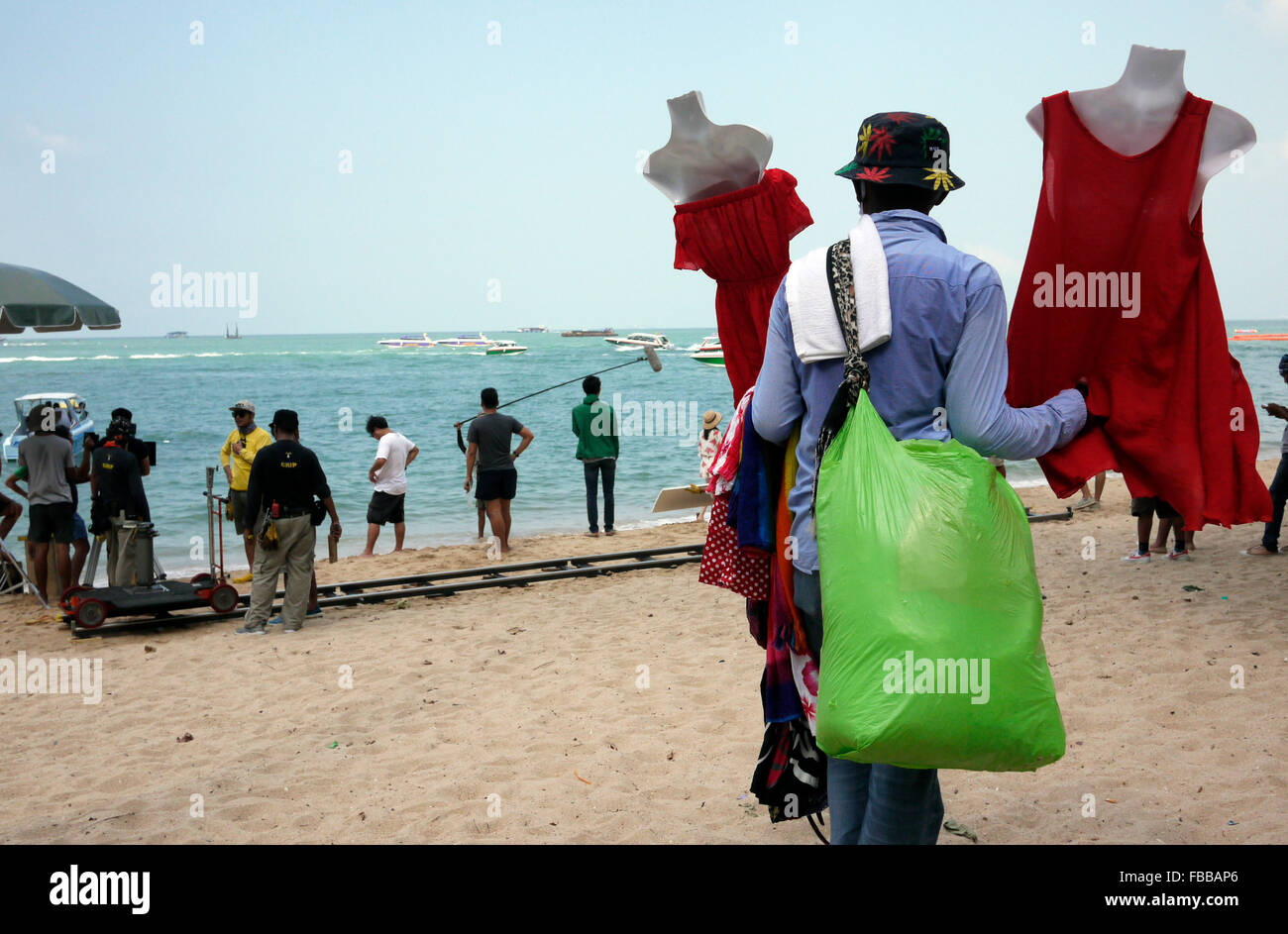 Ein Strand-Anbieter schaut zu, wie eine Szene aus einem Thai Seifenoper am Strand von Pattaya Thailand gefilmt wird Stockfoto
