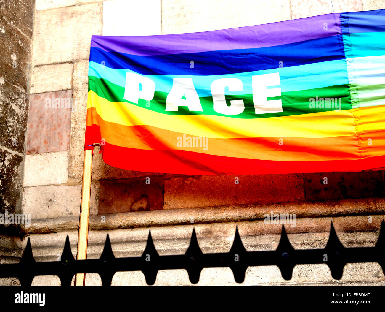 mehrfarbige Regenbogenfahne Frieden während einer Demonstration der italienischen Pazifisten in einer italienischen Stadt hinter Gitter Stockfoto