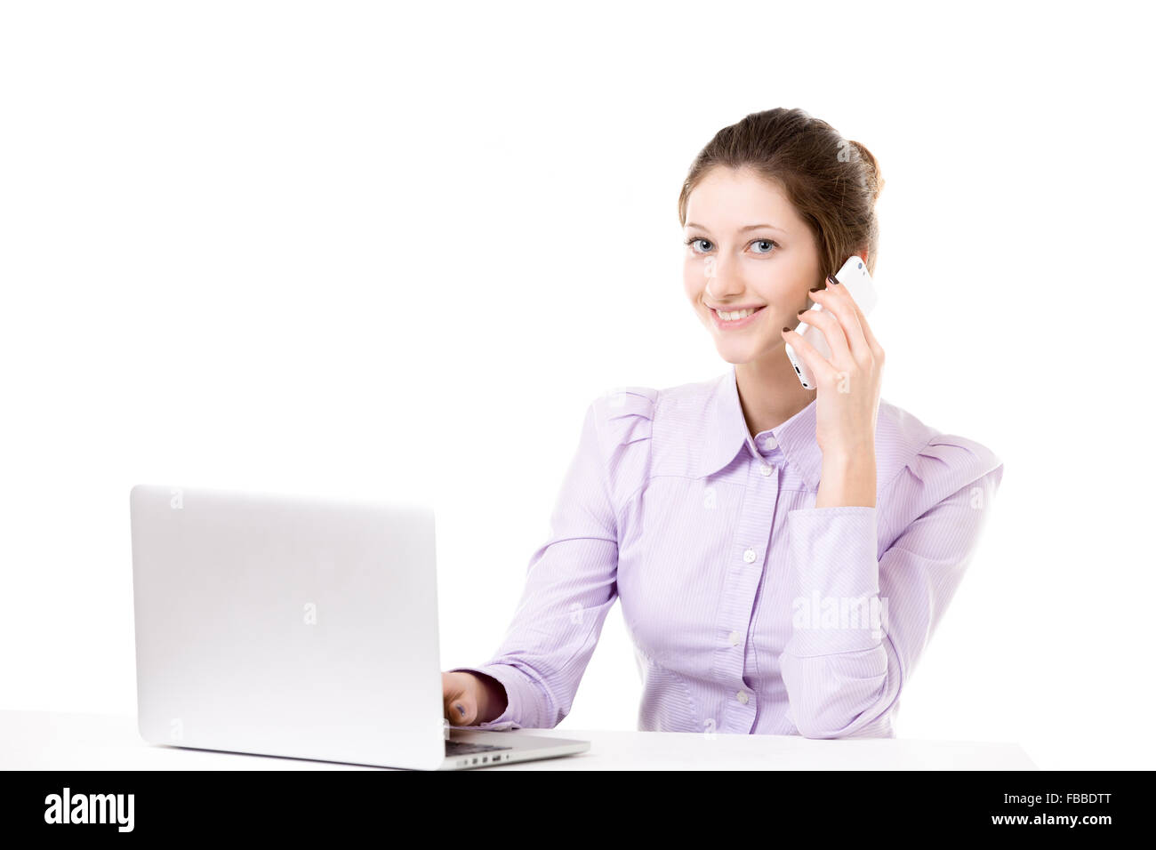 Freundlich lächelnde schöne Büromädchen am Laptop arbeiten, schreiben, telefonieren mit Handy, Anruf, Textfreiraum unter Stockfoto