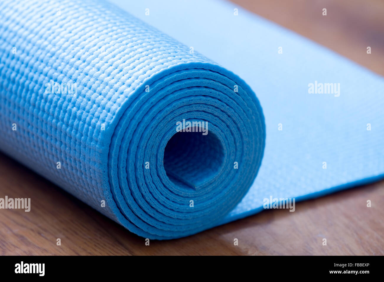 Nahaufnahme des gerollten blauen Yoga, Pilates Matte auf dem Boden. Gesundes Leben, halten Sie sich fit-Konzepte Stockfoto