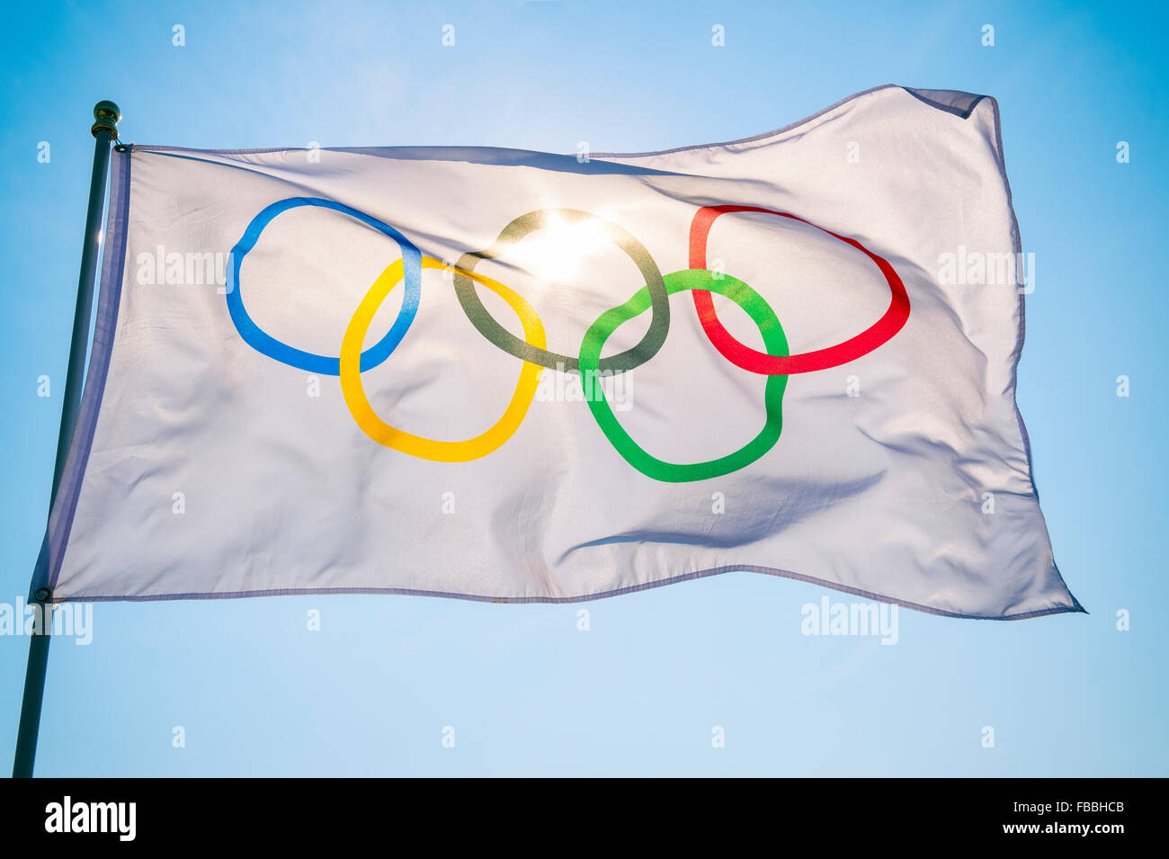 RIO DE JANEIRO, Brasilien - 12. Februar 2015: Eine olympische Fahne flattert im Wind Hintergrundbeleuchtung gegen strahlend blauen Himmel. Stockfoto