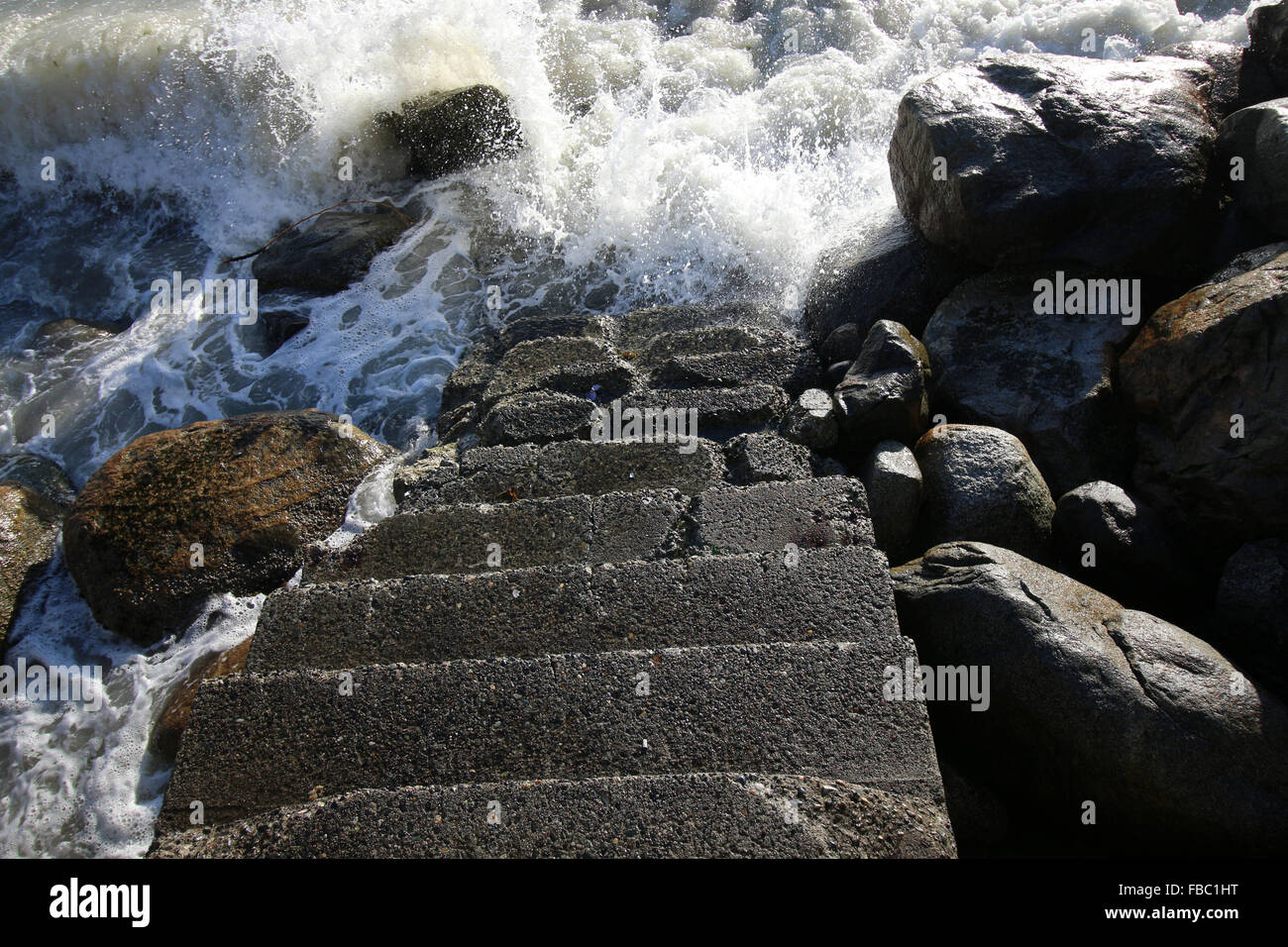 Ozeanwellen an sonnigen Felsen und verwitterten Treppe ins Wasser. Corporate Motivationsposter, Wahlen, Hoffnung, Zeit Stockfoto
