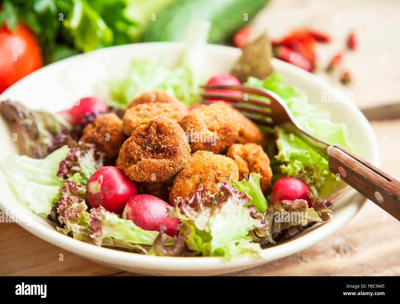 Frisch gebratenes Huhn Frikadellen mit Salat, Radieschen und Gemüse in eine Schüssel geben Stockfoto