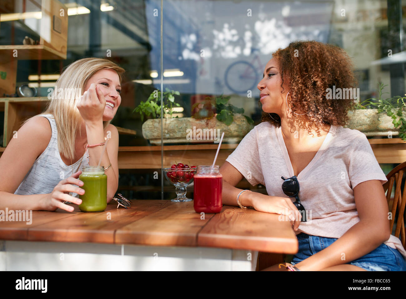 Zwei glückliche Frauen sitzen in einem Restaurant im Freien. Freundinnen genießen Sie Getränke und Chat am Straßencafé. Stockfoto
