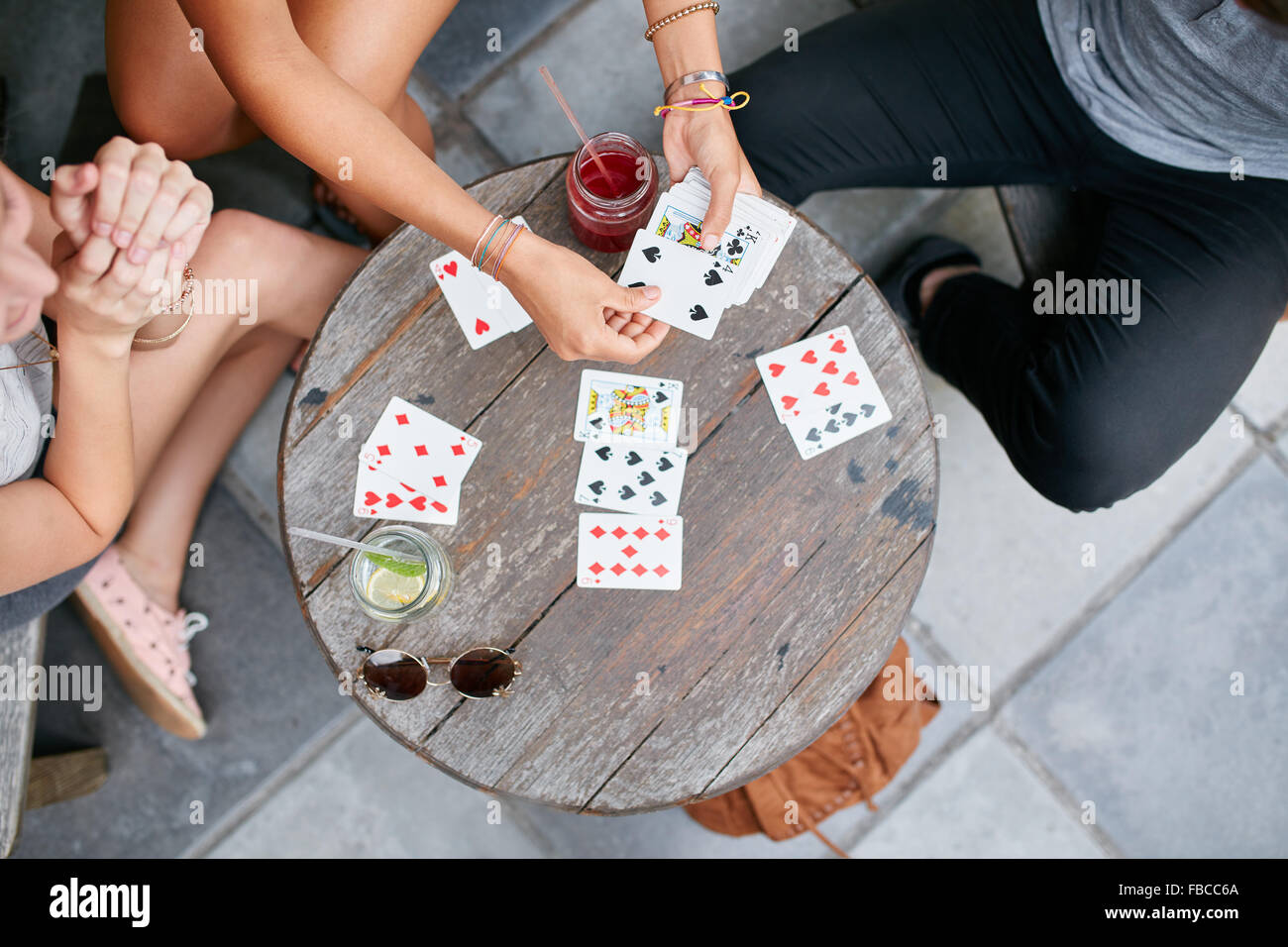 Draufsicht der drei jungen Freunde Spielkarten im Café. Die Jugendlichen spielen Kartenspiel im Coffee Shop. Stockfoto