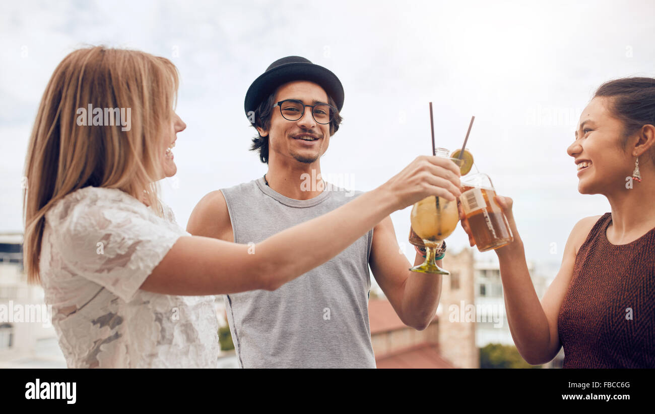 Junge Männer und Frauen, die auf dem Dach Party, toasten Getränke zusammen hängen. Gruppe von Rassen Freunden Spass und Party. Stockfoto