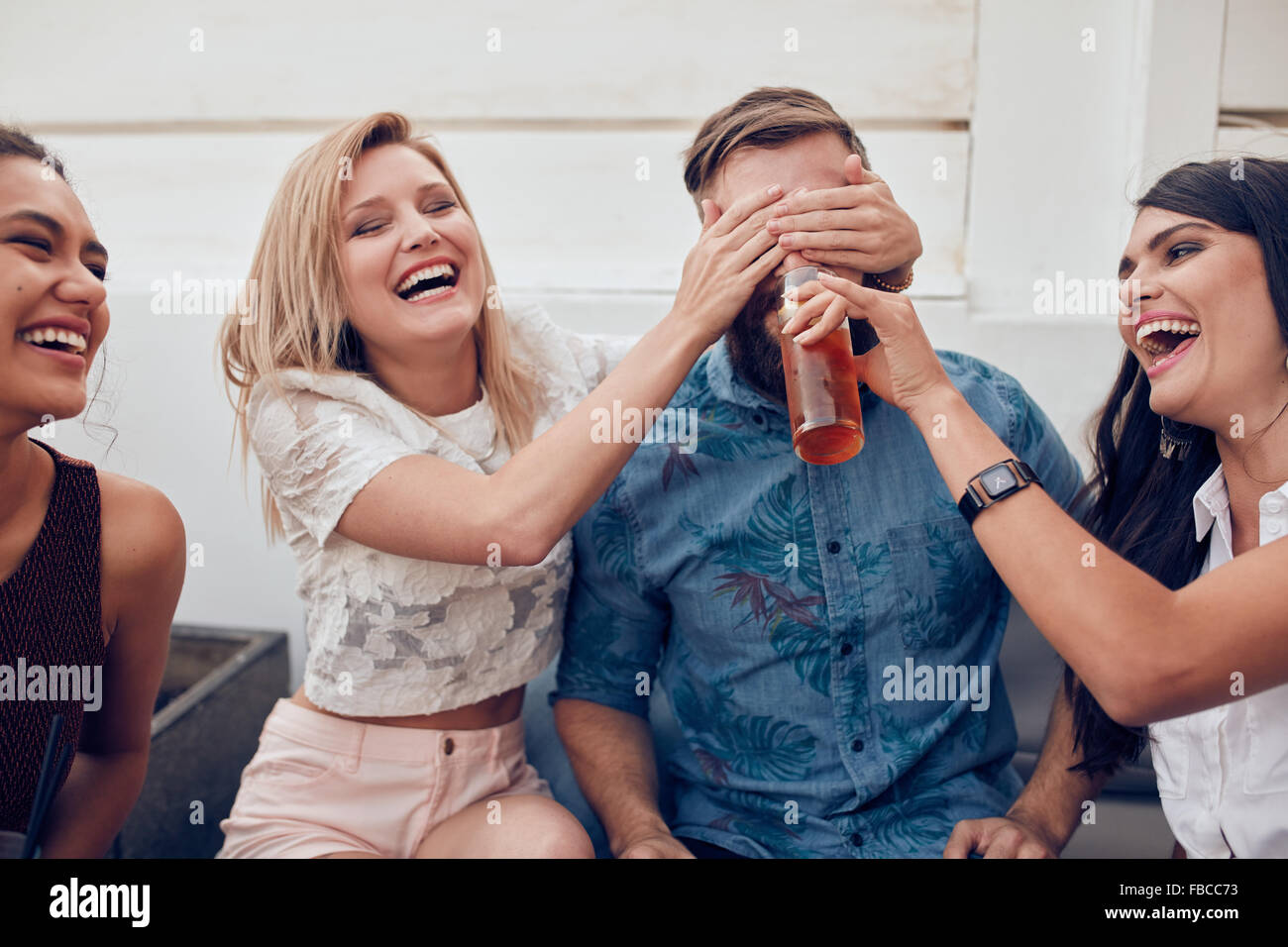 Aufnahme des jungen Menschen sitzen zusammen genießen Partei. Schließen Augen eines Mannes mit einer anderen Frau trinken. Junge Freunde havin Stockfoto