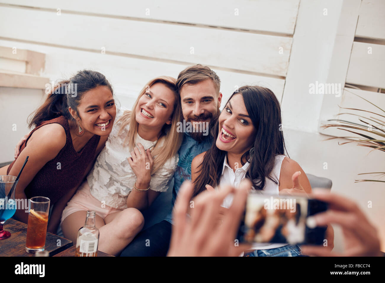 Gruppe von Jugendlichen sitzen zusammen auf einer Party genießen und posieren für ein Porträt. Gemischtrassig erfolgte gestern Kamera smili Stockfoto