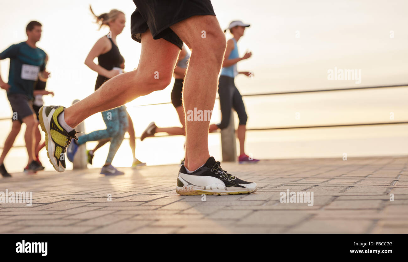Closeup Portrait von Menschen, die unterwegs am Meer mit Fokus auf die Füße der männlichen Läufer. Stockfoto