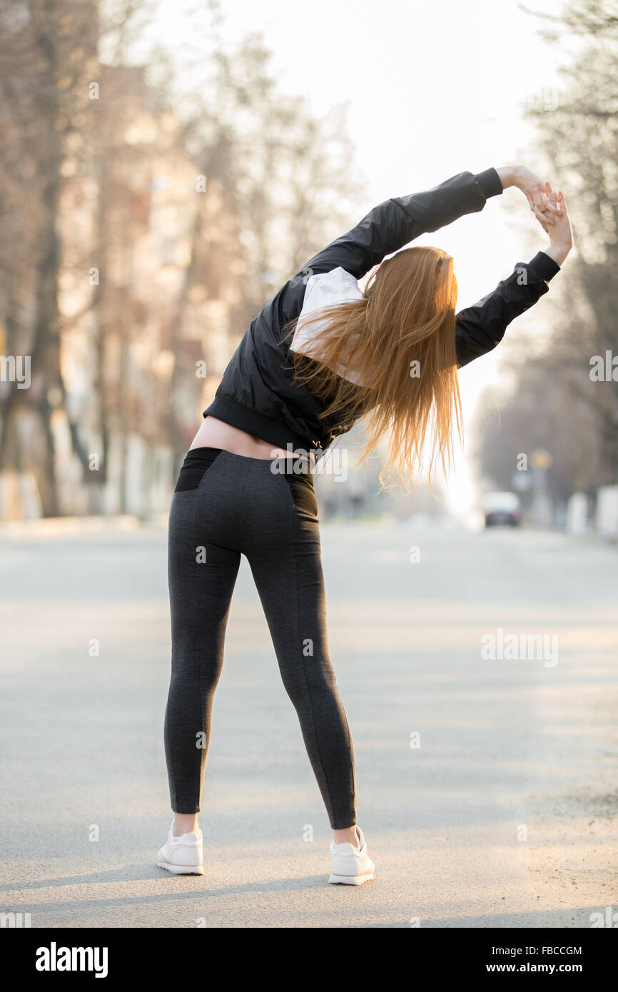 Läufer-Mädchen tun Aufwärmübungen für Wirbelsäule vor morgen Joggen auf der Straße, stretching, laufen zurück v vorbereiten Stockfoto