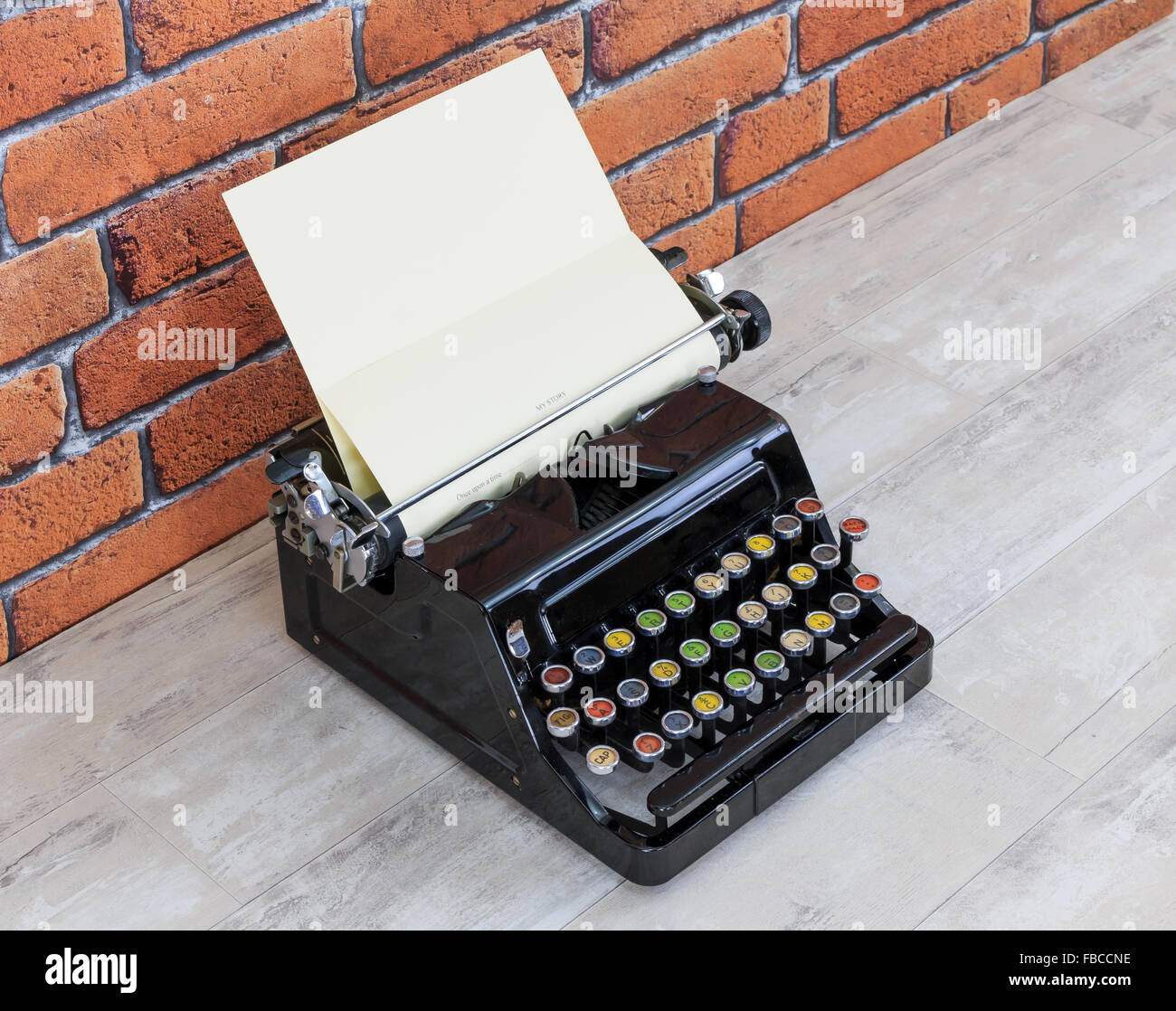 Vintage Schreibmaschine auf alten schäbigen Holzeffekt-Tischplatte mit rotem Backstein Wand Hintergrund Stockfoto