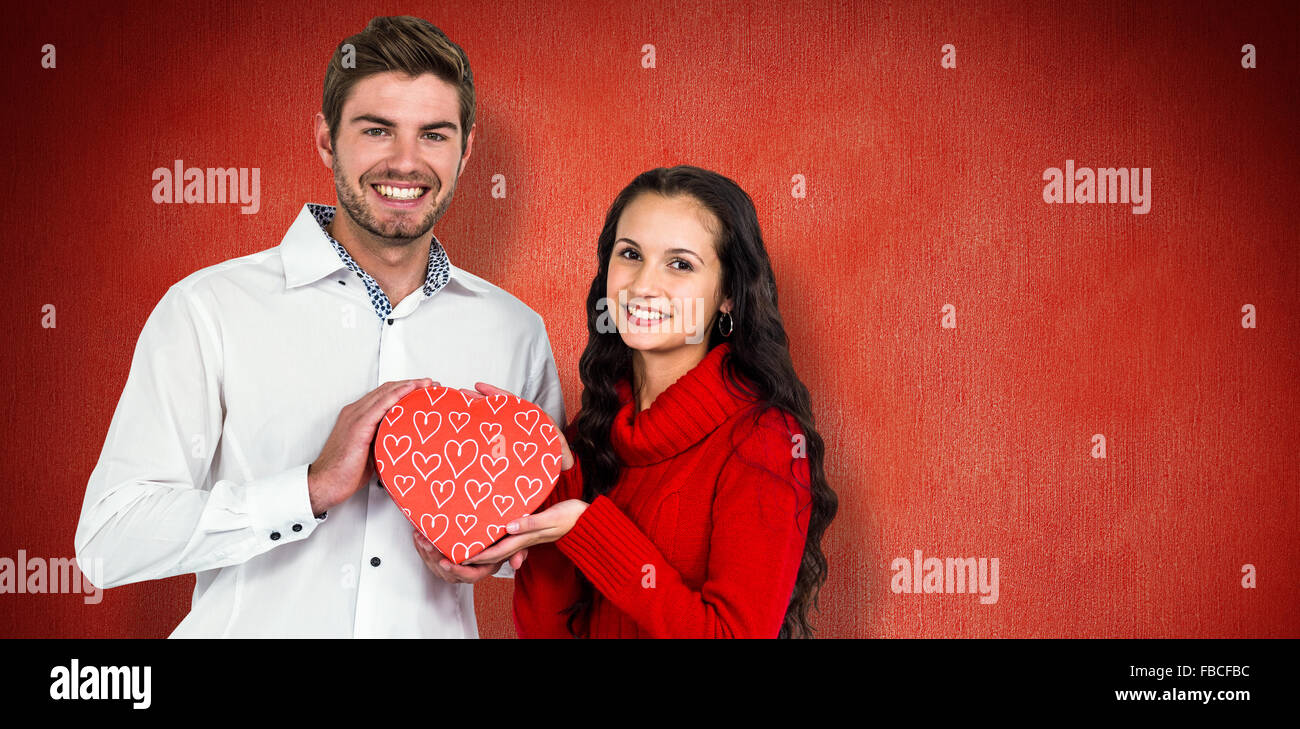 Zusammengesetztes Bild des Paares hält Herz geformt Geschenk-box Stockfoto