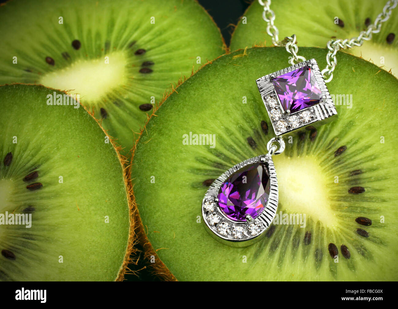 Schmuck mit Edelsteinen und Diamanten auf Kiwi-Frucht-Hintergrund Stockfoto