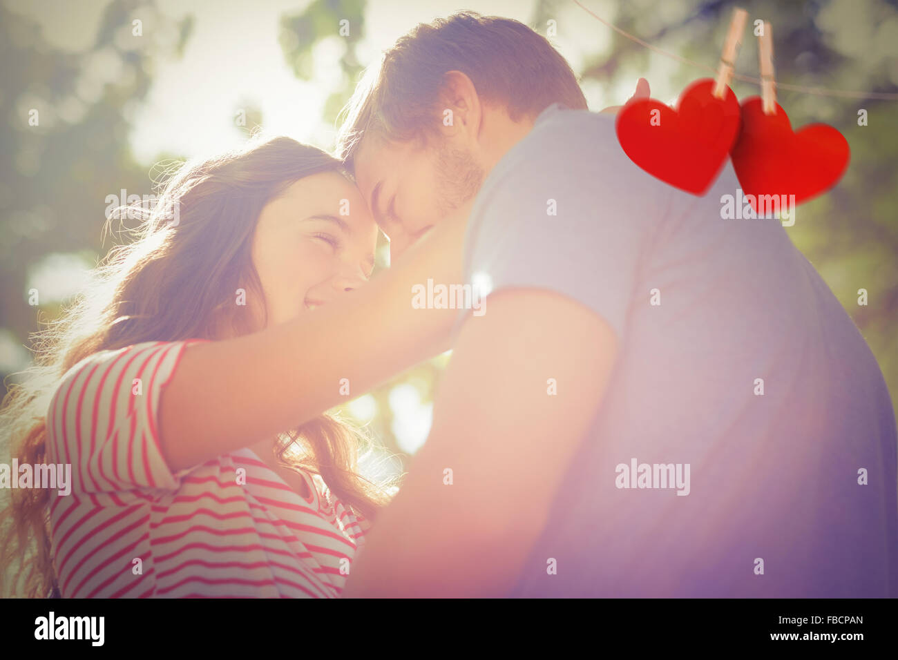 Zusammengesetztes Bild des niedlichen Coupe lächelnd an einander im park Stockfoto