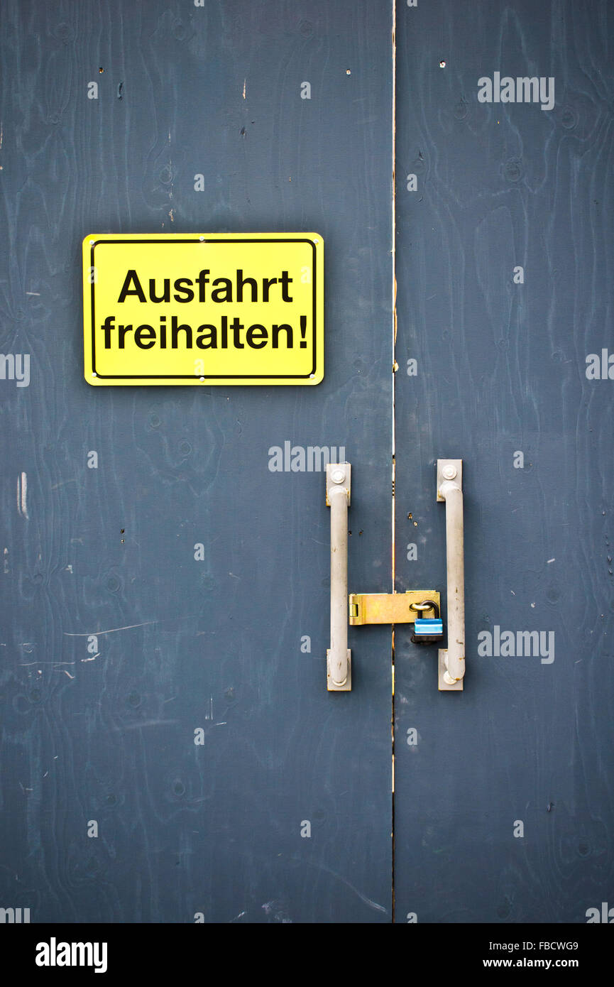 Ein gelbes Schild an einer Tür in deutscher Sprache, die Angabe der Ausfahrt freihalten Stockfoto