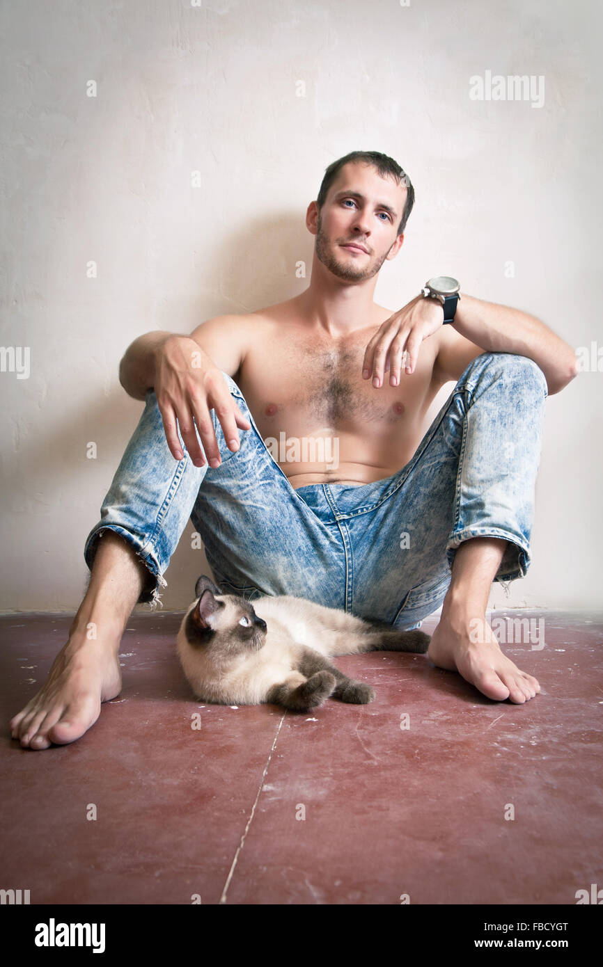 Junger Mann sitzt auf dem Boden mit seiner Katze Stockfoto