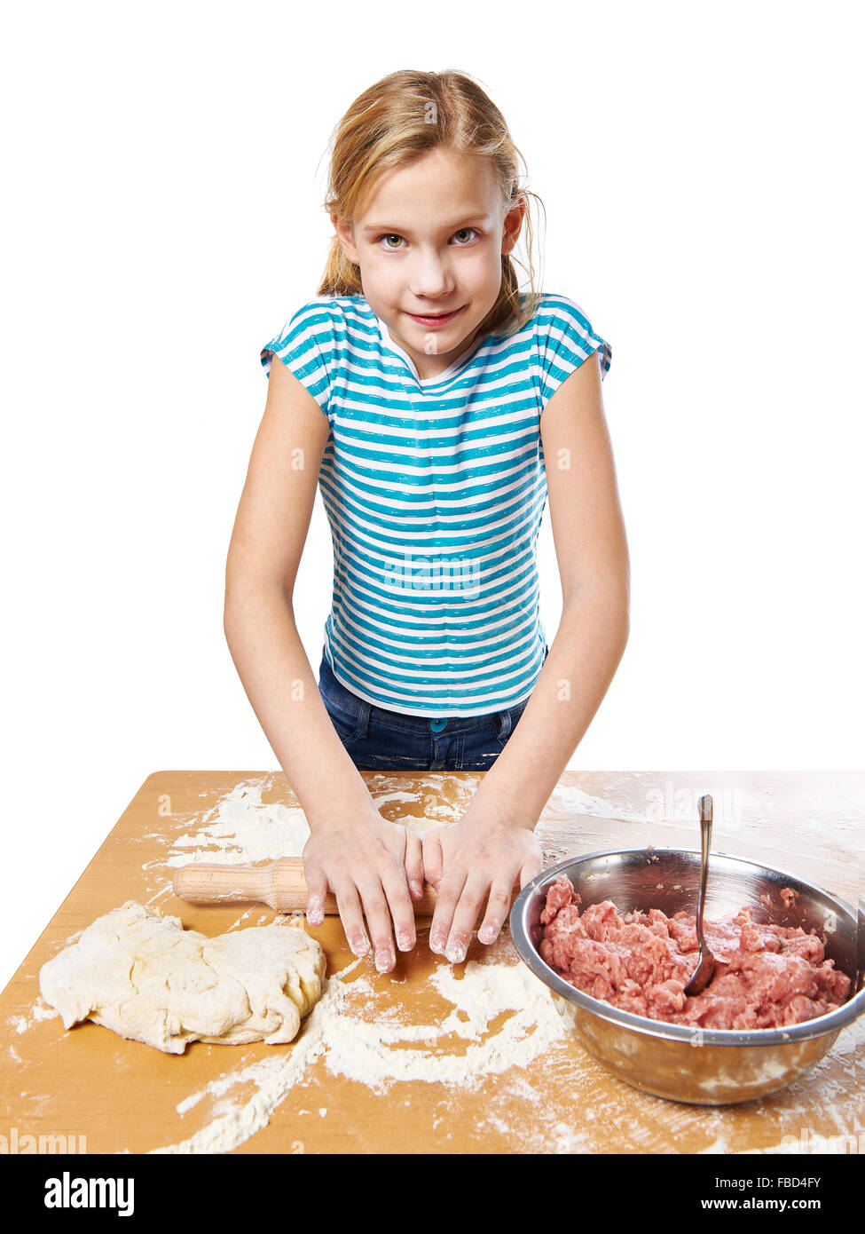 Mädchen knetet Teig am Küchentisch isoliert Stockfoto