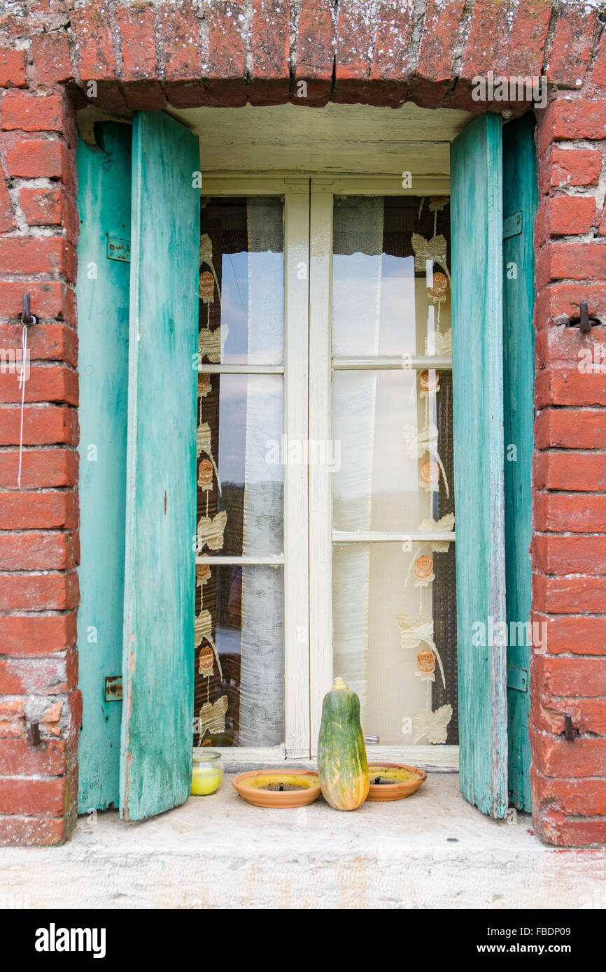 Fenster eines Bauernhauses mit Holzbalkonen und rotem Backstein Rahmen. Stockfoto