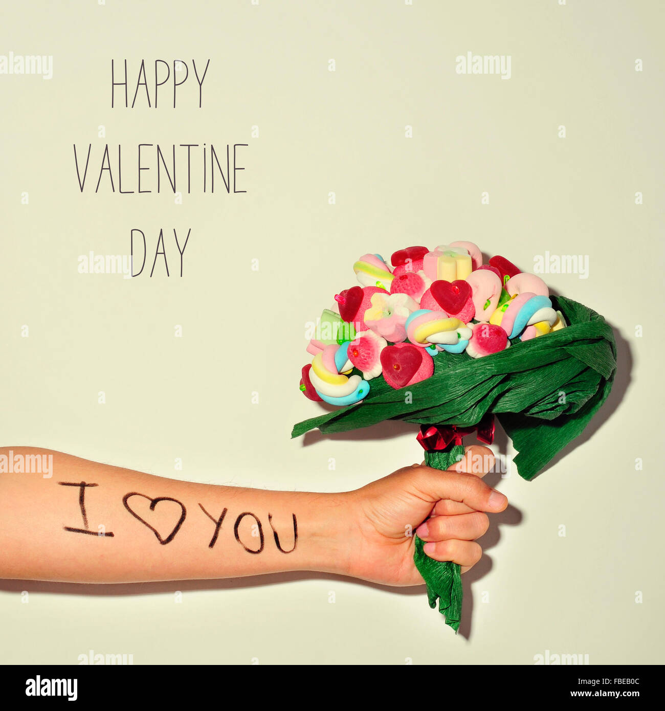 Nahaufnahme eines jungen Mannes mit einem Candy Bouquet mit dem Satz ich liebe dich geschrieben in seinem Unterarm und der Text happy valentin Stockfoto